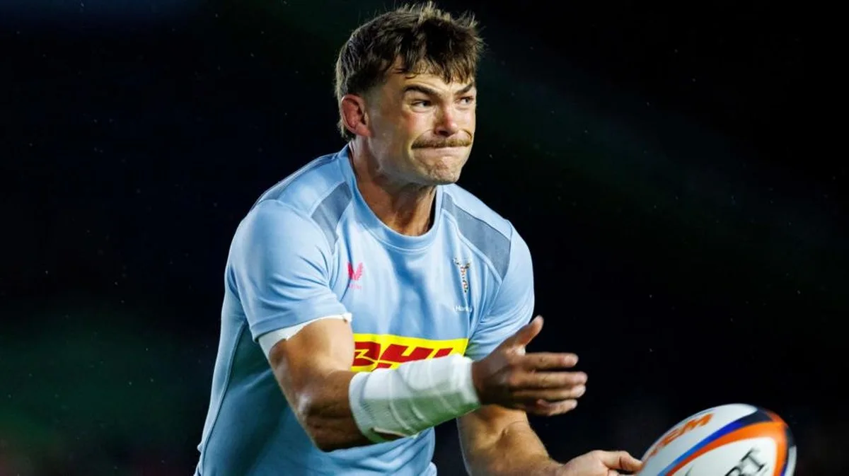 George Furbank, wearing a sky blue Harlequins shirt, throws a rugby ball during a game against Edinburgh