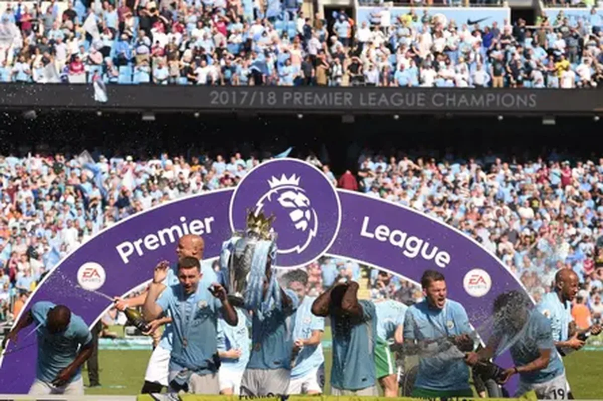 Manchester City players celebrate with the Premier League trophy on the Etihad pitch in May 2018.