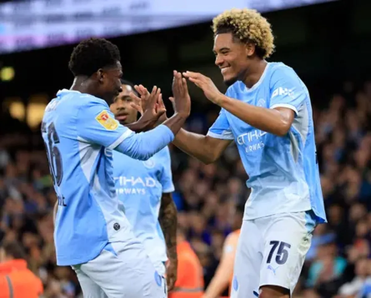 Ryan McAidoo congratulates Floyd Samba for scoring Manchester City’s fourth goal against Norwich.