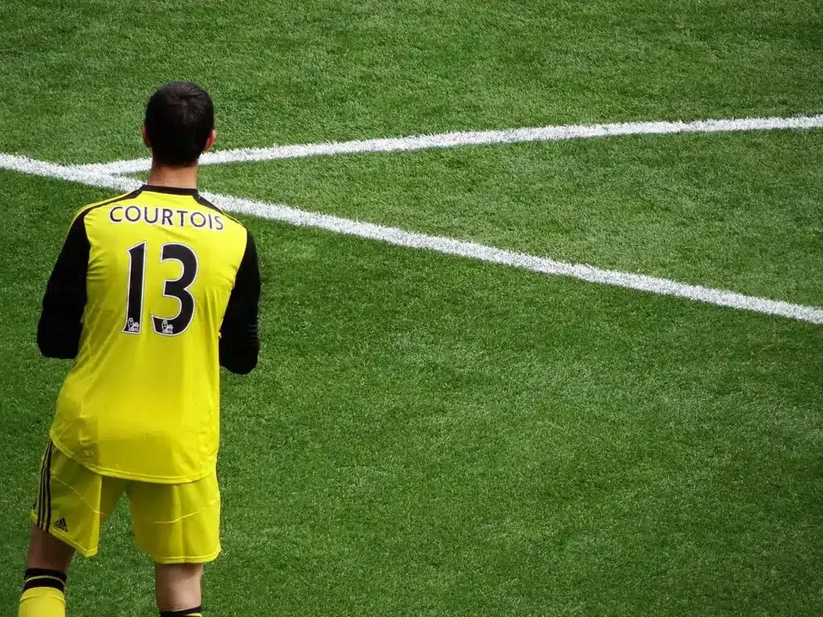 Thibaut Courtois wearing a yellow goalkeeper kit with the name Courtois and number 13 on the back.